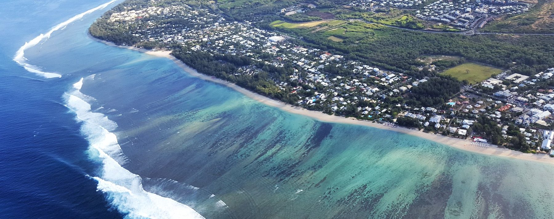 Vue aérienne du lagon turquoise de la côte ouest de La Réunion, avec le récif, la plage et les hauteurs de l'île